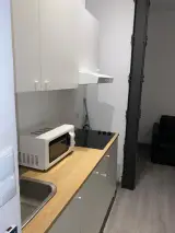 Interior Apartment kitchen with white units, microwave and induction hob on a wooden worktop